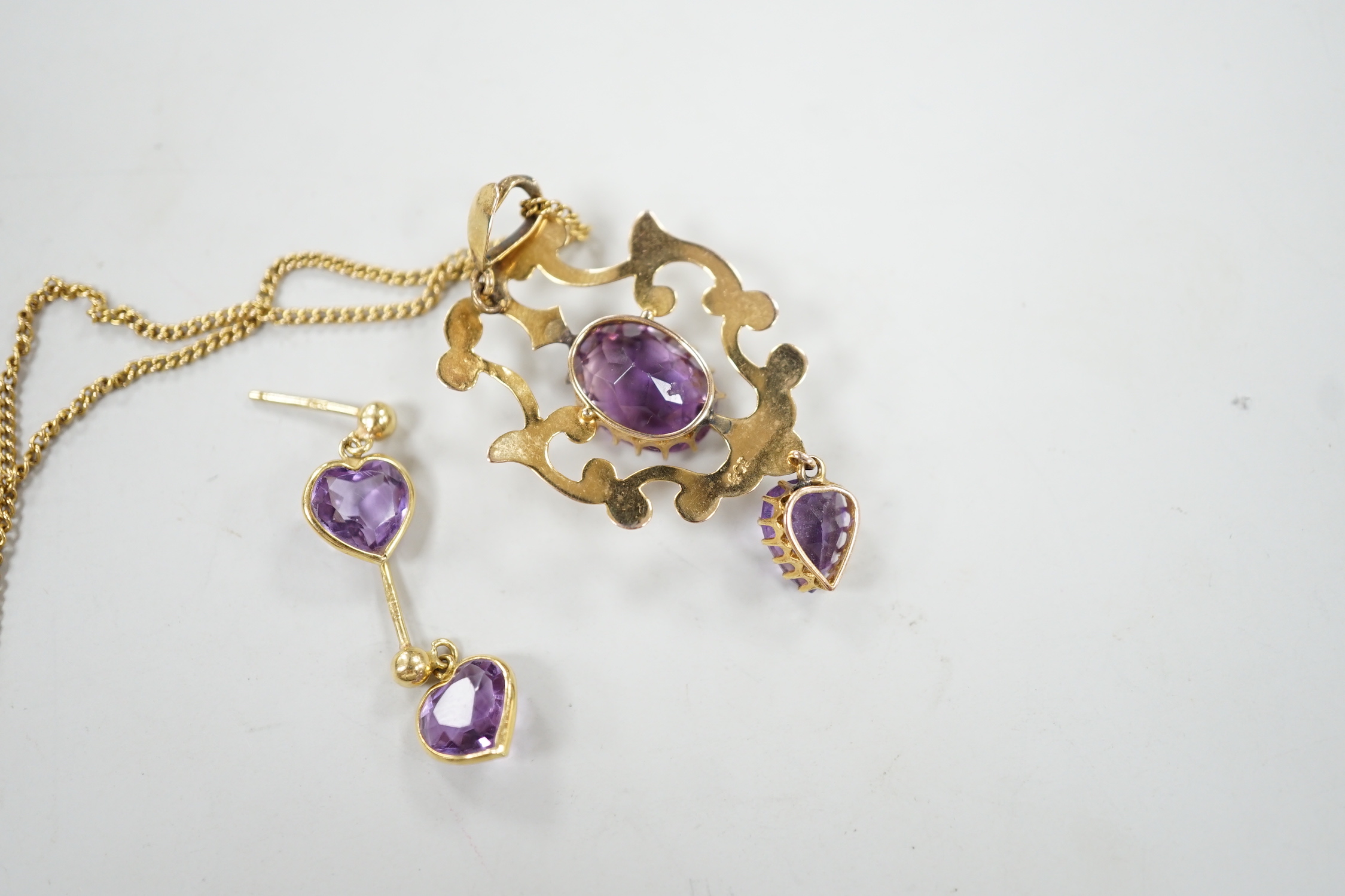 An early 20th century 9ct and two stone amethyst set drop pendant, 40mm, on a 9k chain, 60cm, gross weight 6.8 grams, together with a pair of 18ct gold and heart shaped amethyst set drop earrings, gross 1.6 grams.